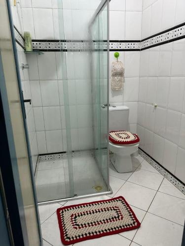 a bathroom with a shower with a toilet and a rug at Casa aconchegante em Barra dos Coqueiros in Barra dos Coqueiros