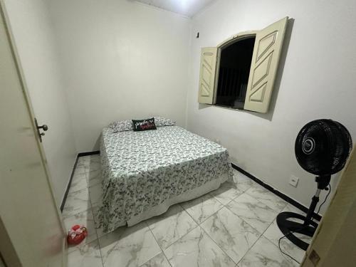 a white room with a bed and a fan at Casa aconchegante em Barra dos Coqueiros in Barra dos Coqueiros