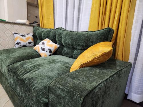 a green couch with pillows sitting in a living room at Ansan Comfort in Gatunga