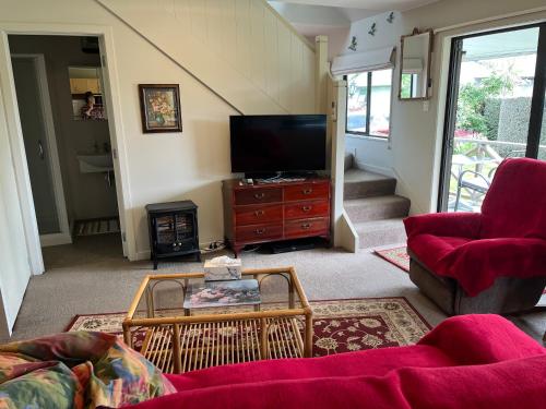 a living room with a tv and a red couch at Pet Friendly Country Cottage in Dunedin