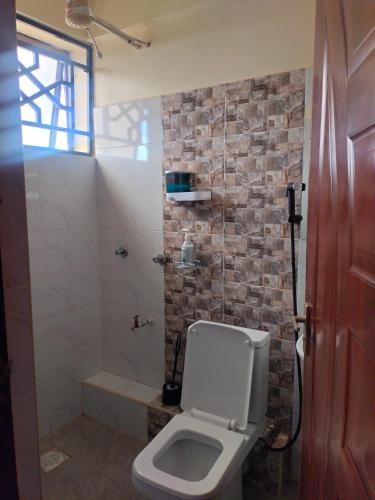 a bathroom with a white toilet and a shower at Khalisee homes studio apartment 4 in Voi