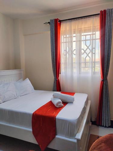 a bedroom with a bed with a red curtain at Khalisee homes studio apartment 4 in Voi