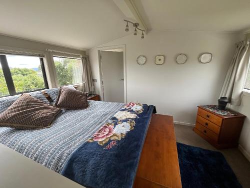 a bedroom with a bed with a blue comforter at Pet Friendly Country Cottage in Dunedin