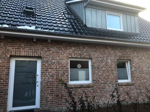 a red brick house with a black roof at Apartment Heidestrauch by Interhome in Thülsfeld