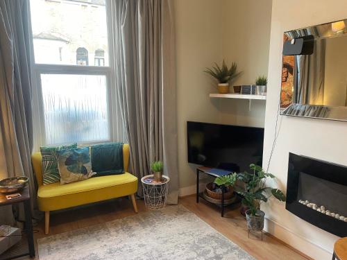 a living room with a yellow chair and a television at 1 Bed Victorian flat Sleeps 4 - Garden & Patio in London