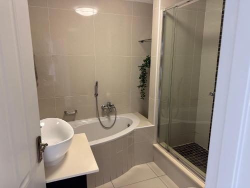 a bathroom with a shower and a tub and a sink at 34 Laguna La Crete in Uvongo Beach