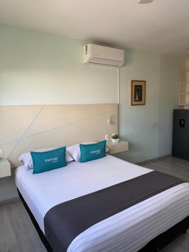 a bedroom with a large bed with two blue pillows at Constanza Lofts Executives en Zapopan Jalisco in Guadalajara