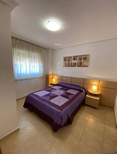 a bedroom with a bed with a purple comforter at Oropesa del Mar Valparaiso Marina Dór in Oropesa del Mar