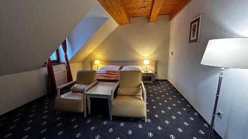 a bedroom with a bed and chairs in a room at Hotel Hradna brana in Bratislava
