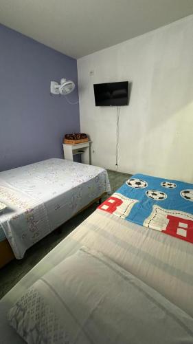 a bedroom with two beds and a flat screen tv at Suites da Bela 02 Caparaó in Caparaó Velho