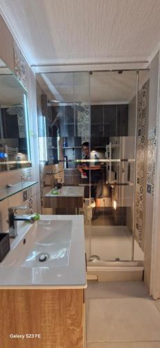 a man is standing in a kitchen with a sink at Hébergement Privé à Larnod in Larnod