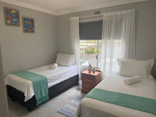 a bedroom with two beds and a window at 64 Laguna La Crete in Uvongo Beach