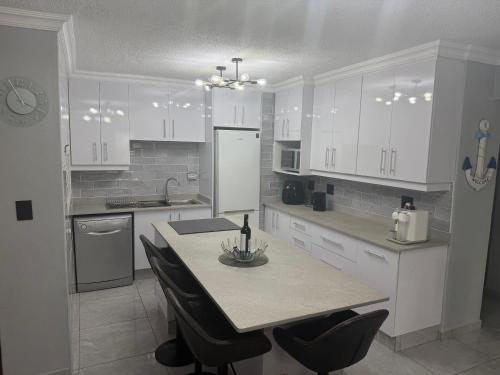 a kitchen with white cabinets and a table with chairs at 64 Laguna La Crete in Uvongo Beach