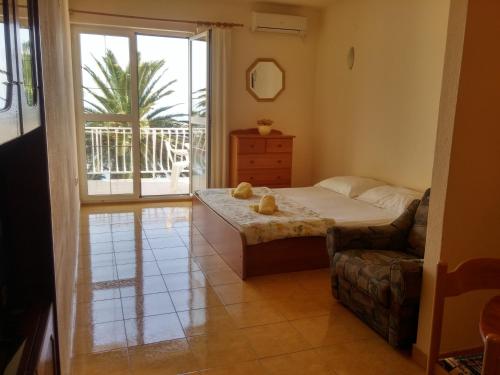 a bedroom with a bed and a chair and a window at Apartments Biser in Podgora