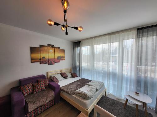a bedroom with a bed and a couch and a window at Studio Lola Jezero in Divčibare