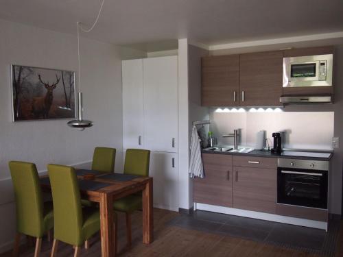 a kitchen with a wooden table and green chairs at Apartment Harzgrün by Interhome in Sankt Andreasberg