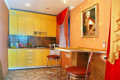 ヘルソンにあるJohn Hovard Apartment Very Centerのキッチン(黄色のキャビネット、テーブル、椅子付)