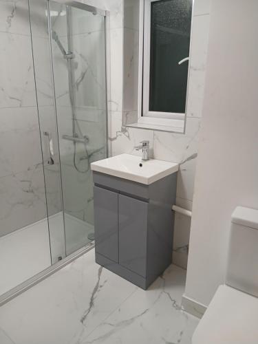a white bathroom with a sink and a shower at Milton Keynes Lettings in Milton Keynes