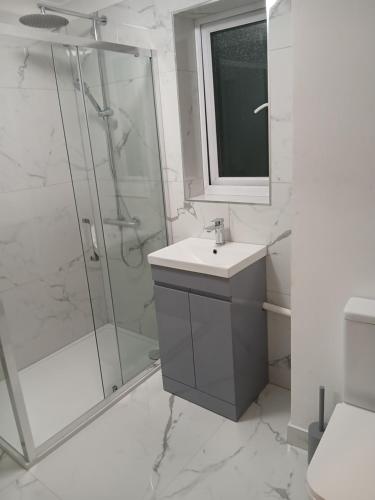 a white bathroom with a shower and a sink at Milton Keynes Lettings in Milton Keynes