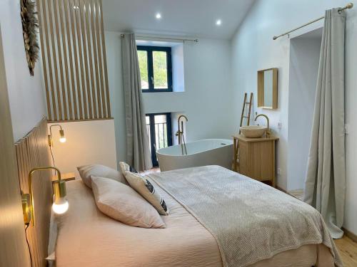 a bedroom with a large bed and a bath tub at Maison de charme - Le Palha in Blesle