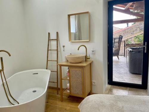 a bathroom with a tub and a sink and a mirror at Maison de charme - Le Palha in Blesle