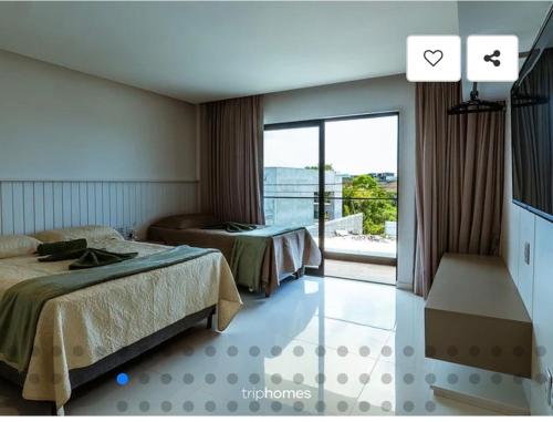 a hotel room with two beds and a balcony at Mansão 5 Suítes - Piscina - Cozinheira - até 16 pessoas - Praia Milionários - Ilheus in Ilhéus