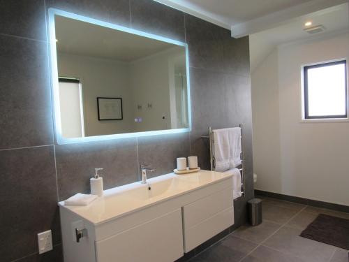 a bathroom with a sink and a large mirror at Pine Holt Cottage in Warkworth