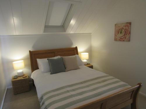 a bedroom with a large bed with two lamps at Pine Holt Cottage in Warkworth