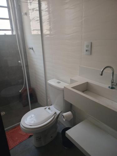 a white bathroom with a toilet and a sink at CASA ENSEADA - Ótima localização in Guarujá