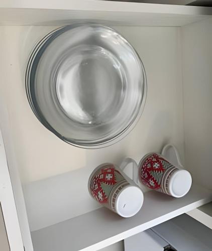a plate and two cups on a shelf at Casa Simples e Funcional em Araxá in Araxá