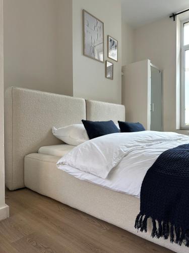 a bedroom with a bed with white sheets and blue pillows at Luik city center in Liège