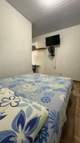 a bedroom with a bed with a blue and white comforter at Suites da Bela 06 Caparao in Caparaó Velho