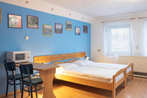 a bedroom with a bed and a table and a blue wall at Apartment Jursport in Závažná Poruba
