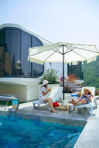 two women sitting on lounge chairs next to a swimming pool at Zeyzid Glamping Sheki in Sheki