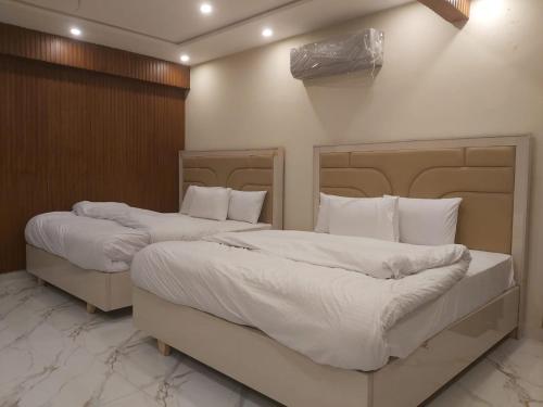 two beds in a hotel room with white pillows at Dove INN Express II in Lahore