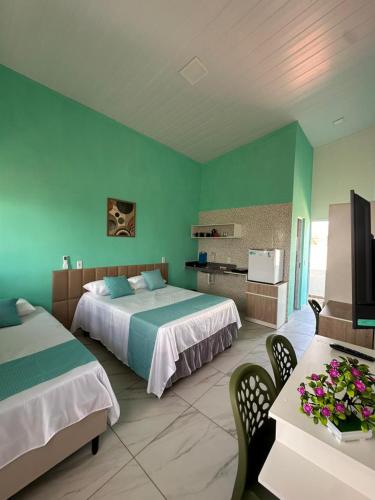 a bedroom with two beds and a table with flowers on it at Mar e Sol Tabatinga in Nísia Floresta