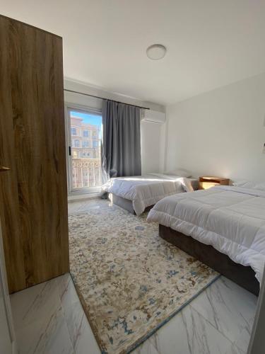 a bedroom with two beds and a large window at Central Park hotel apartment in Madinaty