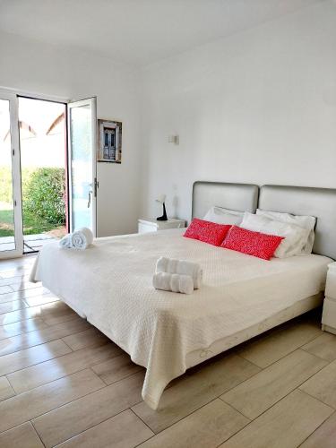 a white bedroom with a large bed with red pillows at Maria's Village in Tavira