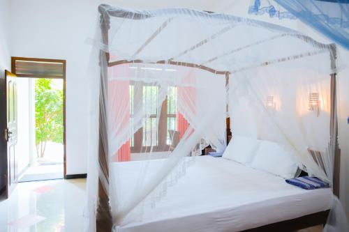 a white bed with a canopy in a room at Raviru Guest Mirissa in Mirissa