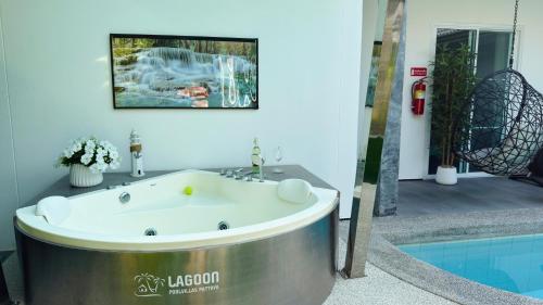 a bath tub in a bathroom next to a swimming pool at Lagoon Poolvillas Pattaya in Ban Huai Yai
