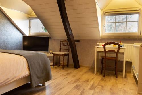 a bedroom with a bed and a desk with two chairs at Le Monciat in Lessines