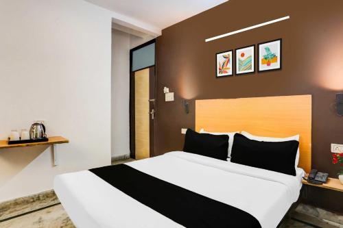 a bedroom with a large white bed with black pillows at Hotel O KL khari Near Ashram Mein Metro in New Delhi