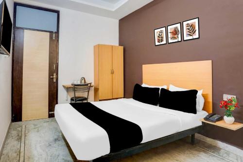 a bedroom with a large white bed with black pillows at Hotel O KL khari Near Ashram Mein Metro in New Delhi