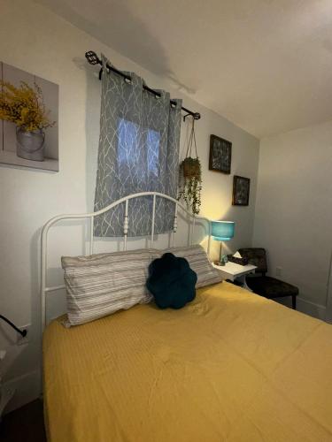 a bedroom with a bed with a yellow bedspread and a window at Peaceful in Moncton