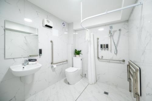a white bathroom with a toilet and a sink at Solsen Flexi-Stay & Motel in Auckland