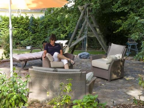 a woman sitting in a chair under an umbrella at Apartment mit Pool und überdachtem Balkon by Interhome in Beerfelden
