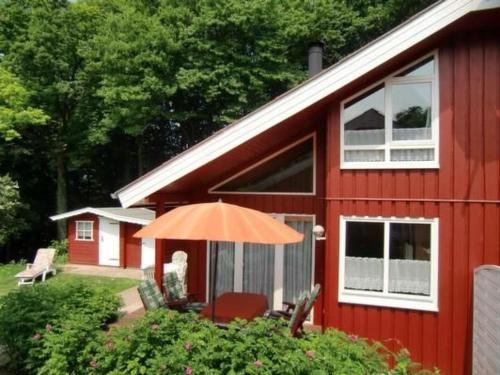 a red house with an umbrella and chairs in front of it at Holiday Home Marx by Interhome in Bremke