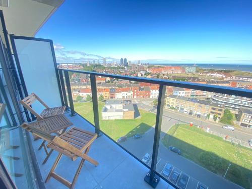 a chair on a balcony with a view of a city at Joy at sea in Bredene-aan-Zee