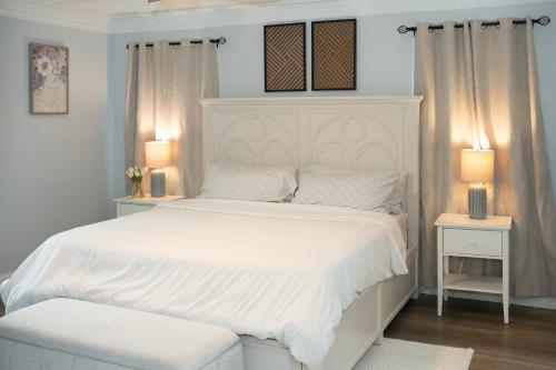 a bedroom with a white bed with two tables and two lamps at DFW Spacious Cozy Modern Villa in Grand Prairie