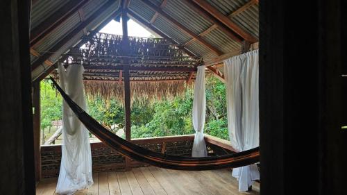 a hammock in a room with a large window at Florada in Ilha do Maiandeua